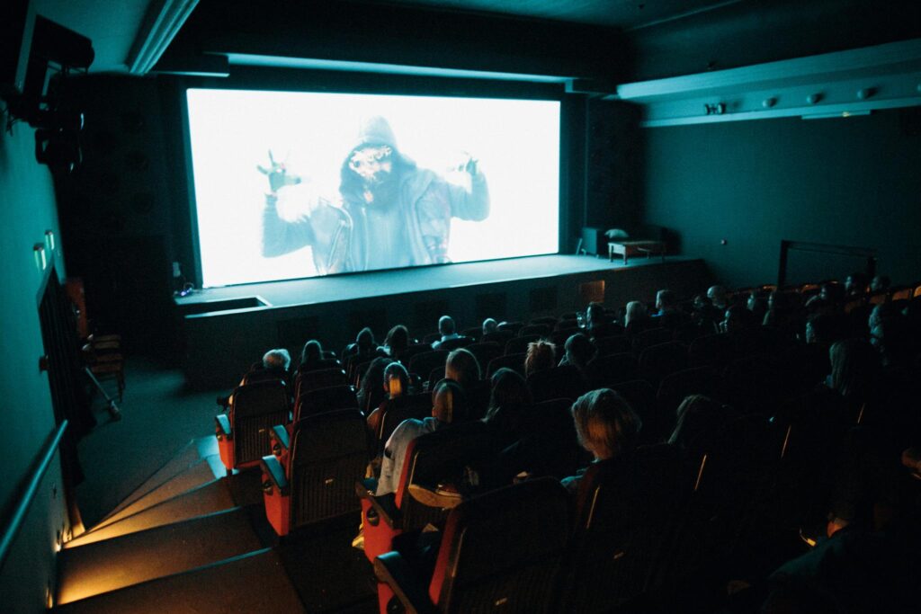 Building a Loyal Blog Audience: Strategies for Engagement and Growth Crowded cinema theater with audience watching a movie on a large screen in a dark setting.