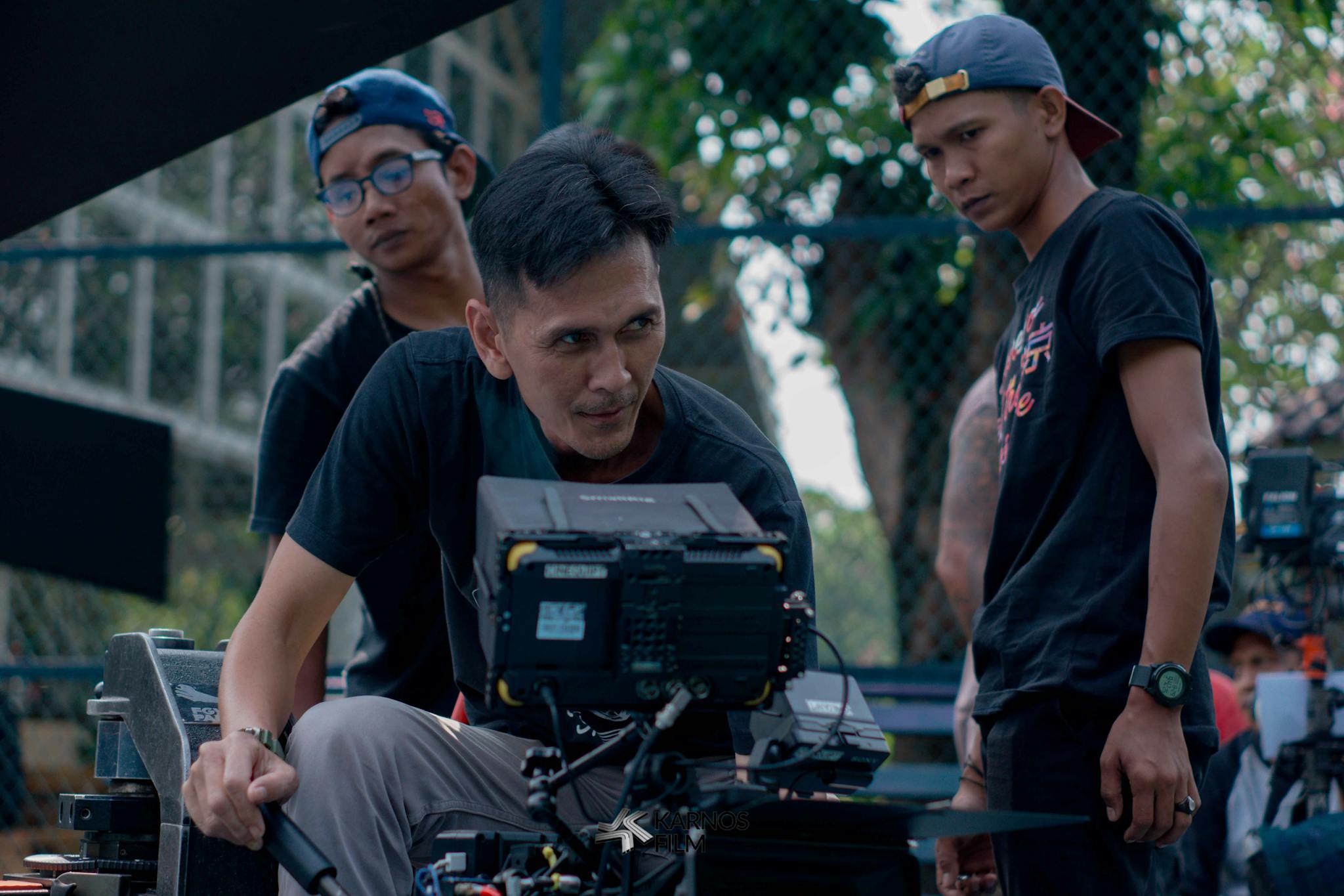 Group of filmmakers reviewing footage on set outdoors, focused on camera equipment.